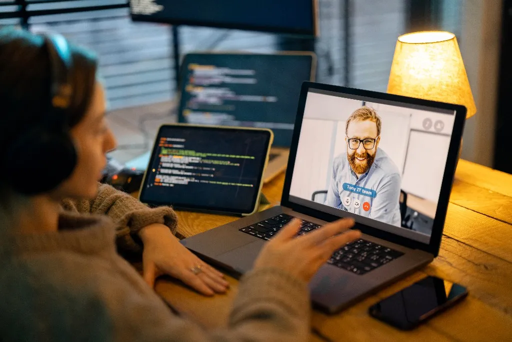 Person on a video call with a remote developer while code is open on a nearby screen